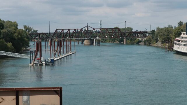 View of river dock and metal bridge across river showing an urban waterscape with docking infrastructure and a calm water surface