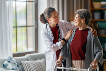 Obraz premium Smiling Female Doctor Assisting Elderly Woman with Walker at Home