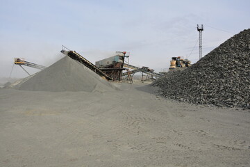 Fototapeta premium Crushed stone pile close up with industrial gravel quarry crushing plant machine on background concept