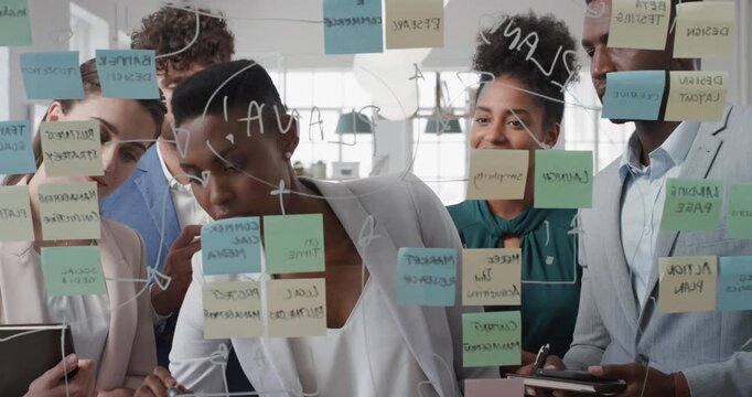 Woman, writing and team at office with review for notes on glass wall or planning at marketing company. Business people, talk or group by window, feedback or project management at advertising agency
