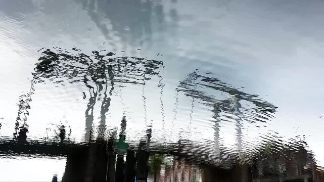Urban signs and sky reflected in rippling water