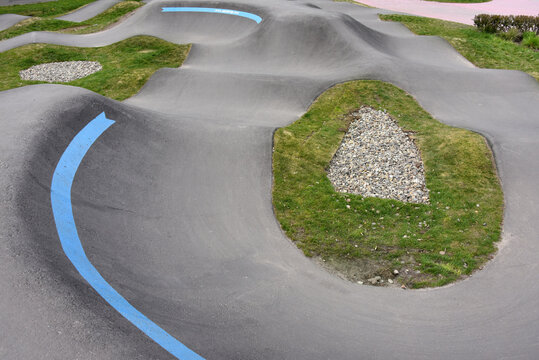 Curved concrete pump track for bikes and skateboards in a public park