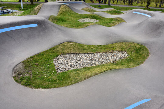 Curved concrete pump track for bikes and skateboards in a public park