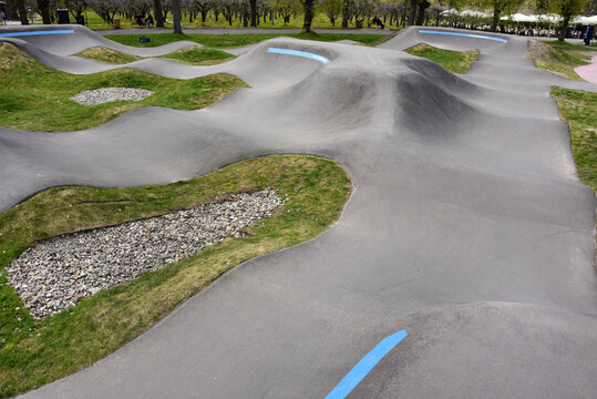 Curved concrete pump track for bikes and skateboards in a public park