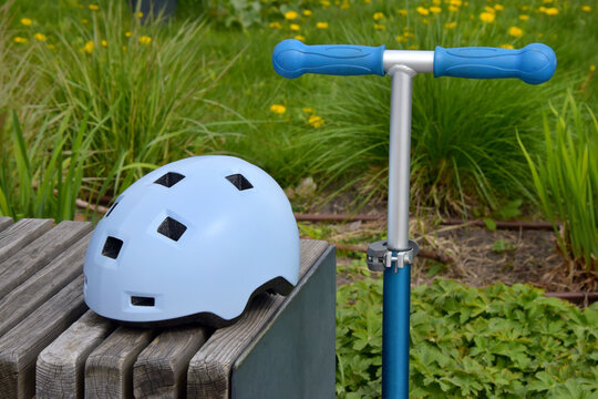 Child's blue helmet with a scooter at a park bench, safe summer