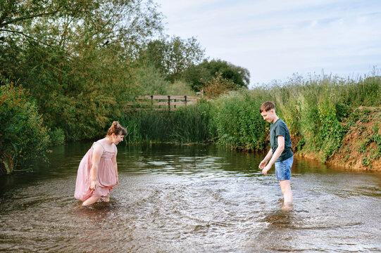 Brother and sister standing together in shallow stream
