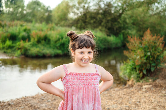Smiling child girl standing beside a stream in summer