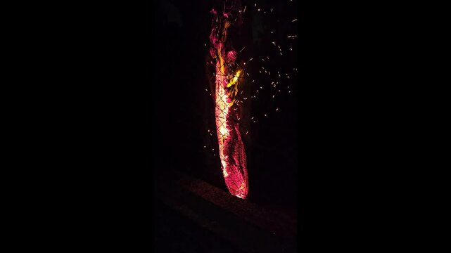 Tall fire log burning brightly in the dark