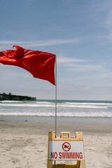 Obraz premium Red flag and no swimming sign on beach