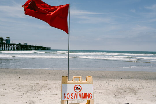 Red flag no swimming warning sign on a beach