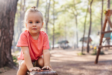 Blonde toddler girl with a top knot in a forest © Cavan