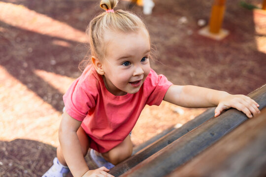 Cute toddler girl climbing on a playground