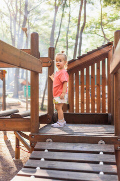 Curious toddler girl on a wooden playground in the park