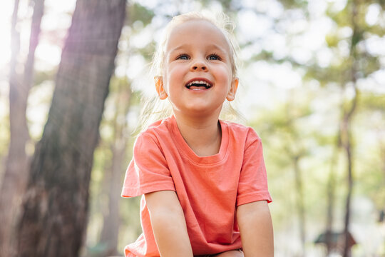 Happy little girl smiling in a sunny forest