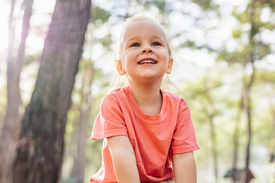 Adorable little girl smiling in sunny forest