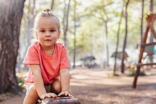 Blonde toddler girl with a top knot in a forest