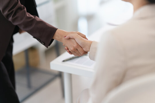 Two business people shaking hands to finalize job offer agreement in professional office meeting