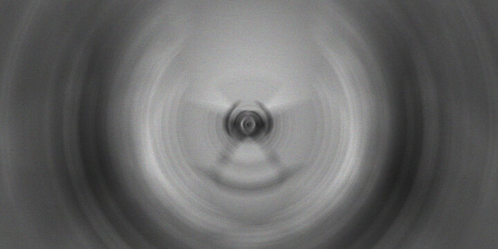 Monochromatic radial blur effect creating concentric circles with a central focal point.
