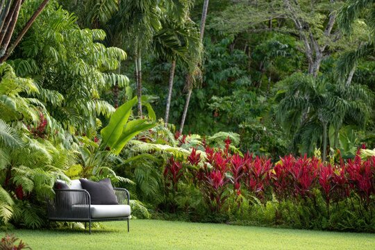 Gray metal armchair with dark cushions rests on a green lawn