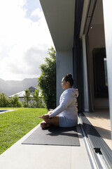 Fototapeta premium Yoga mat is resting on patio threshold and facing green lawn with distant mountain ridge