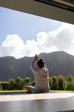 Yoga mat is lying on veranda floor, facing dramatic mountain range under partly cloudy sky