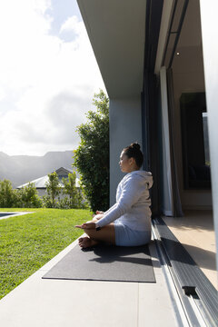 Yoga mat is resting on patio threshold and facing green lawn with distant mountain ridge