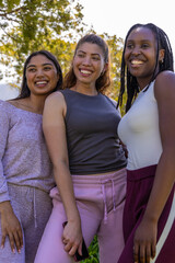 Obraz premium African American women smiling, posing in park wearing track pants, one holding smartphone