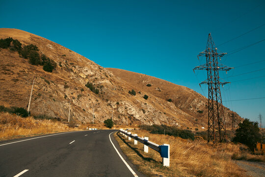 Highway in the mountains with clear blue sky and white clouds.