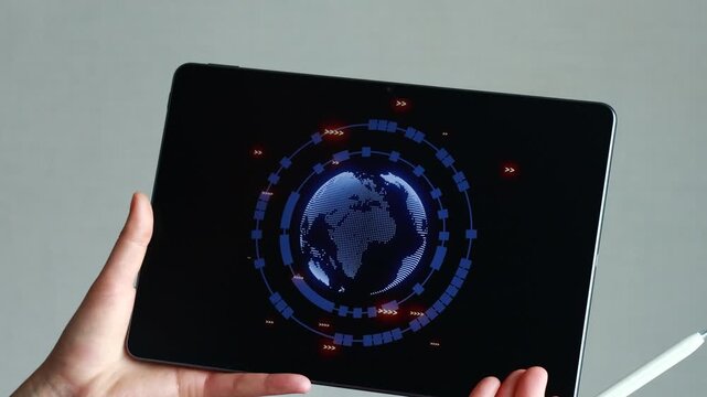 A person holds a tablet that displays a digital globe and data points. The setting appears to be modern, and the activity seems focused on technology and information.