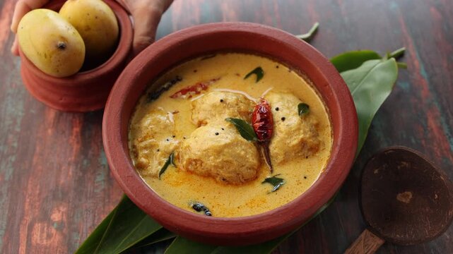 Traditional yellow mango curry or Mampazha Pulissery sweet and sour dish Kerala India . Made from organic raw ripe mango, coconut milk, seasoned with curry leaves, mustard, Indian red Kashmir chilli.