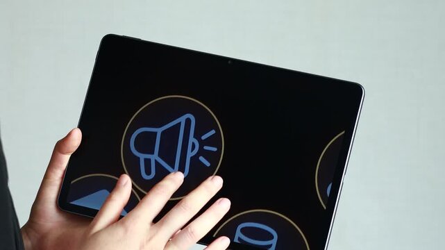 A person uses a tablet with several icons displayed on the screen. The focus is on finance and technology, set in an office environment with good lighting.