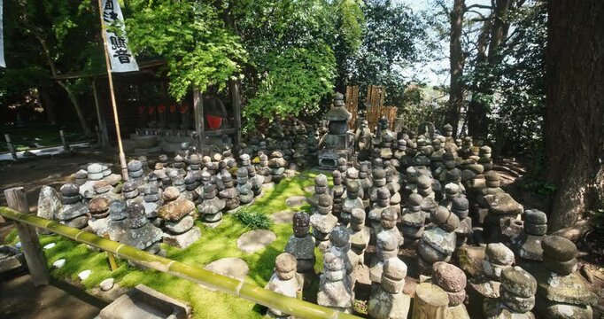 Rows of Stone Jizo Statues on Moss Ground At Japanese Shrine - Steady Cam Slow Motion