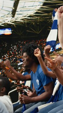 Vertical Video Tense blue team supporters reacting to close call during live soccer match in a crowded stadium, wait for final whistle, multigenerational supporter group shows suspense and
