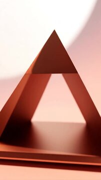 A metallic pyramid shape sits on a soft pink surface background