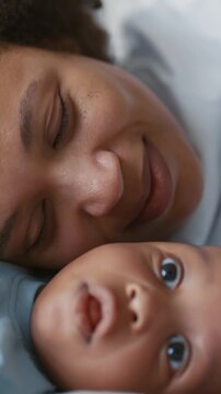 Charming black infant boy or girl enjoying time with mother, happy family,. Beautiful african woman smiling when looking at cute little child, mom and son lying in bed, motherhood and childhood