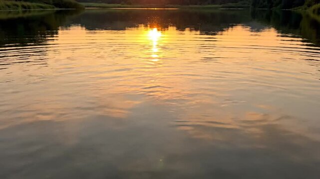 Sunset over calm water surface reflection.