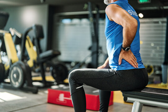 Senior mature man exercising at gym, suffering a back pain, neck pain,  injury health care