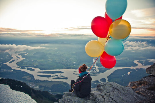 Woman with colorful balloons on a mountain summit