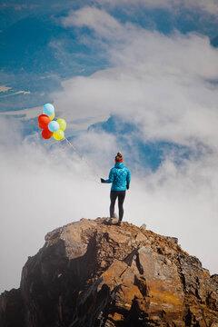 Adventurous woman hikes foggy mountain with balloons