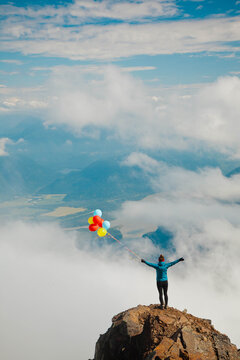Woman with colorful balloons on mountain summit