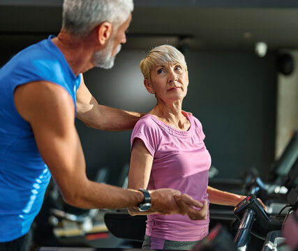Portrait of a senior couple exercising in a gym, mature couple running using treadmill machine equipment, healthy lifestyle and cardio exercise vitality and active senior, coach training help and supp