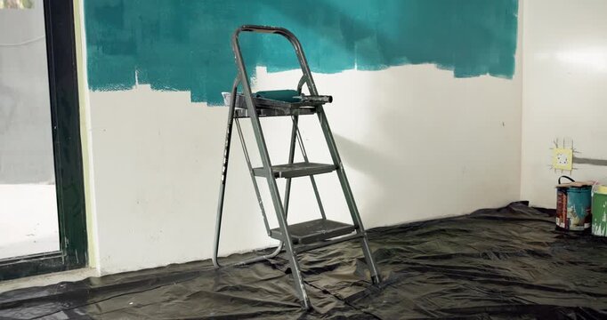 Ladder, wall and painting for renovation with empty room for property development with color. Interior design, tools and equipment with tarp cover for splatter, application and gear for real estate