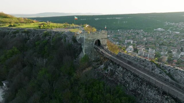 Ovech fortress aerial drone view Bulgarian flag rocky cliff Provadia Bulgaria medieval stone walls city panorama travel heritage slow motion Balkans landmark historic summer overview