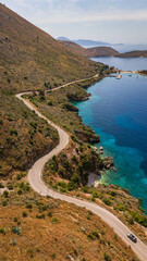 Fototapeta premium Aerial drone perspective of the scenic SH8 coastal highway winding along the steep mountain ridges of the Albanian Riviera. Breathtaking Mediterranean landscape