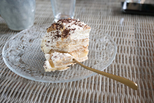 A portion of cake on a plate with multiple layers of cream.
