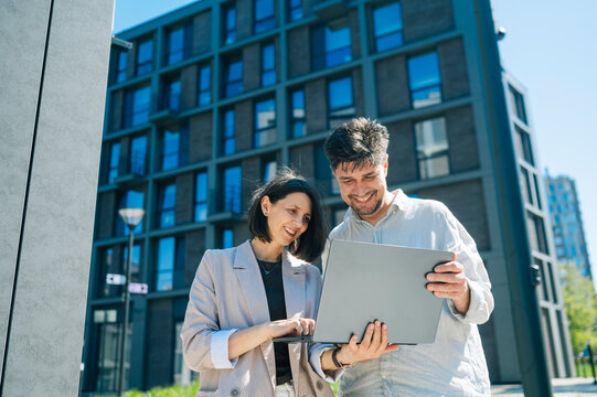 Colleagues looking at laptop outside modern apartment building