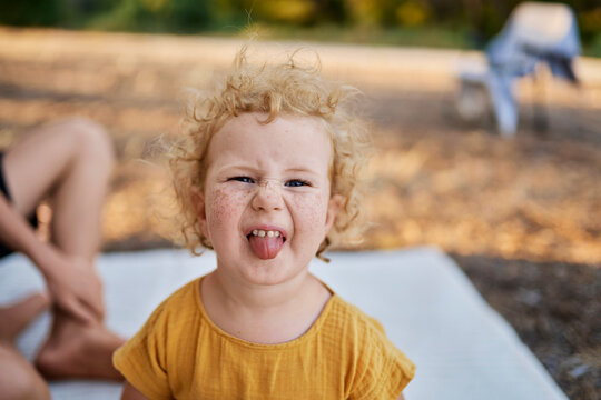 Innocent girl sticking out tongue sitting in park