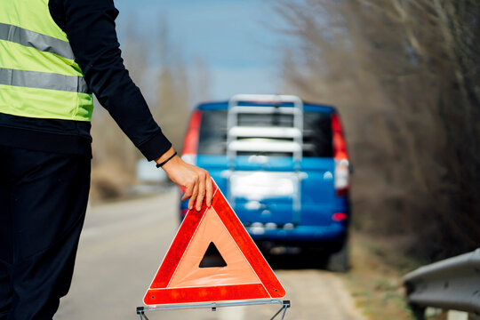 Man putting warning triangle on country road by van breakdown