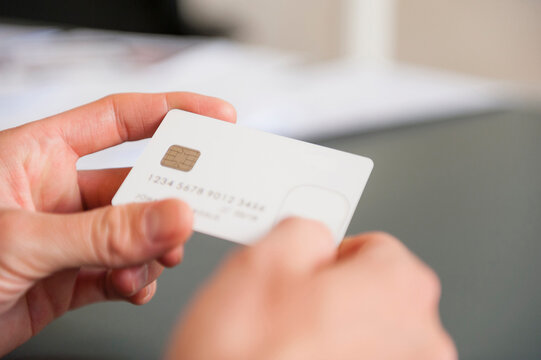 Hands of mid adult man holding blank white credit card