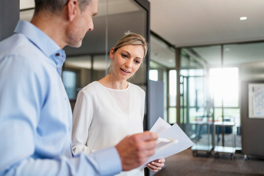 Businessman and businesswoman with digital tablet and documents talking in office